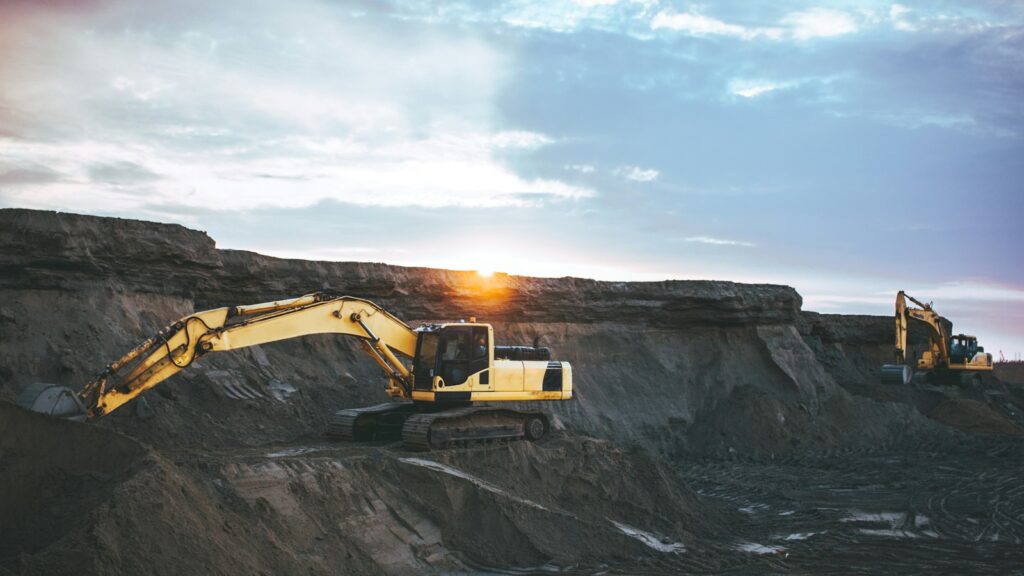Excavator on rocky terrain, representing the ore feed for ball and SAG mills