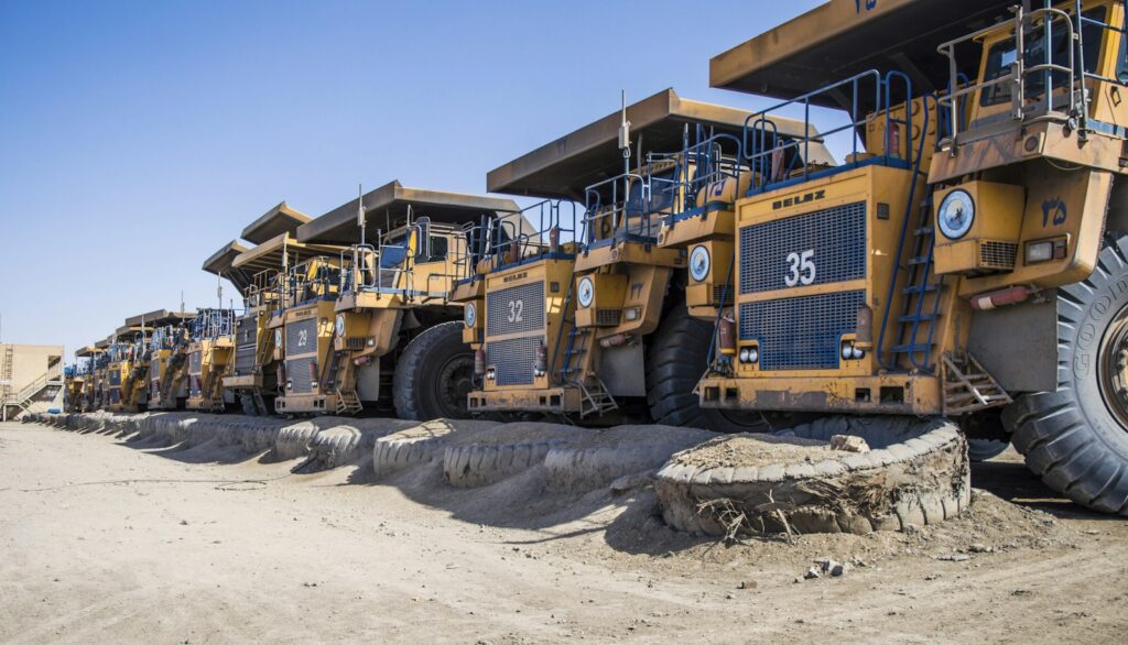Row of heavy mining trucks used to haul feed material to crushing and milling equipment