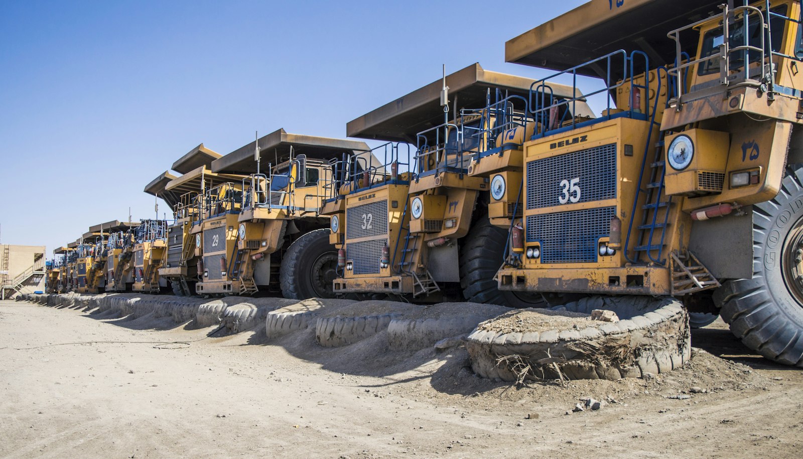 Row of heavy mining trucks used to haul feed material to crushing and milling equipment