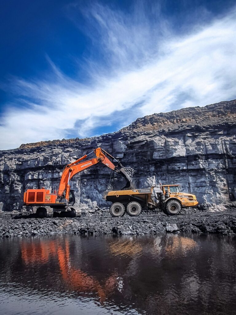 Excavator loading a dump truck with quarried rock feed for an impact crusher